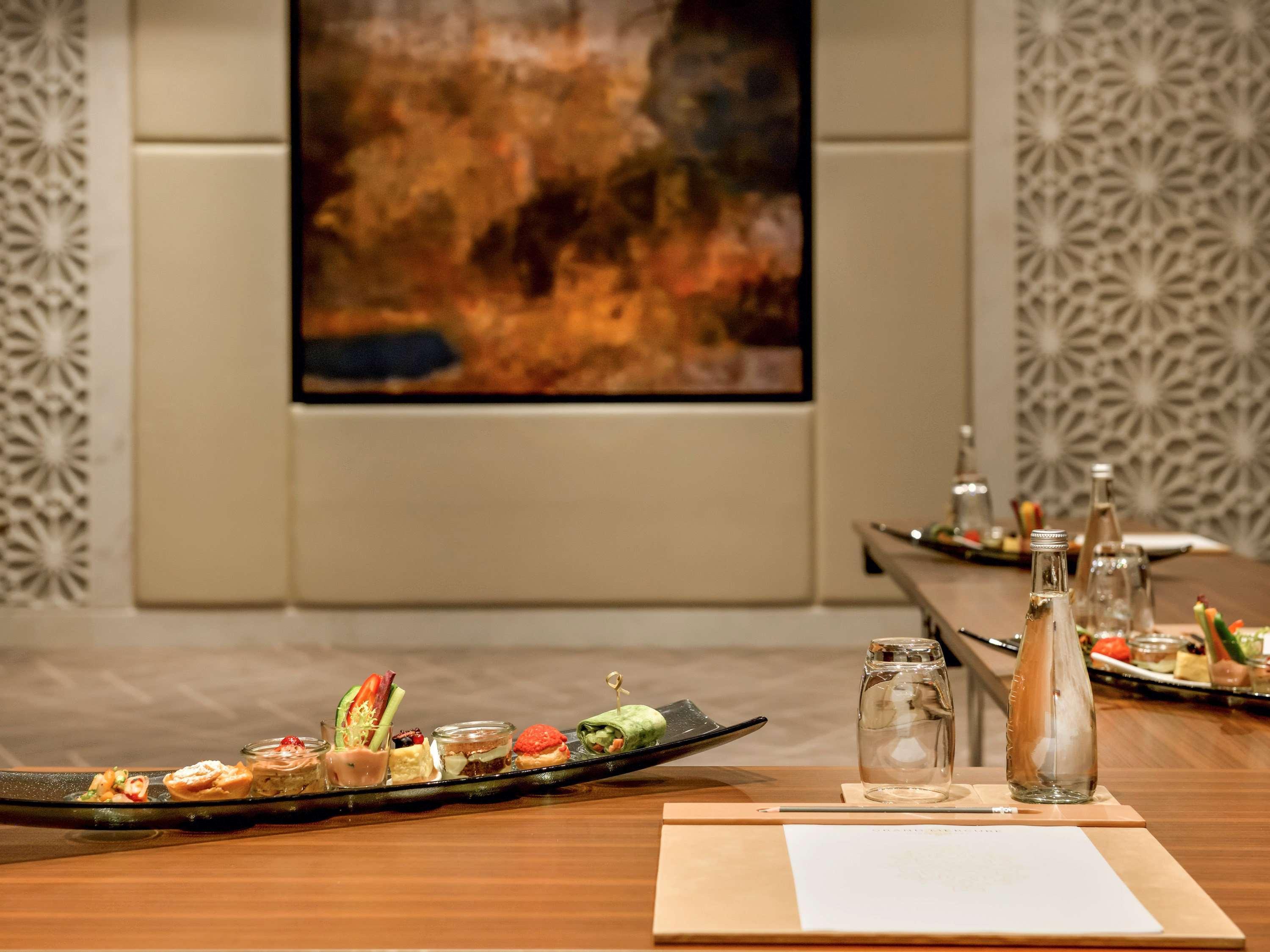Grand Mercure Dubai City Exterior foto The photo shows a stylish dining setting featuring a wooden table with a long, elegant platter of assorted dishes, including sushi and garnishes. In the background, there is a large artwork that appears to be an abstract painting, which adds a vibran