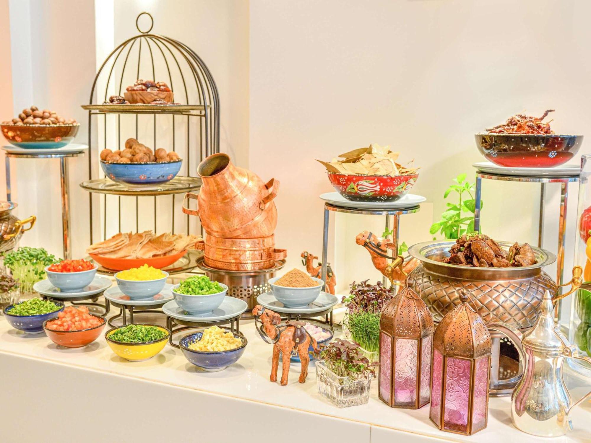 Grand Mercure Dubai City Exterior foto The photo displays a vibrant and elaborate buffet setup featuring a variety of dishes. On one side, there's a decorative metal stand with several tiers holding different types of foods, likely including cooked meats and other savory items. 

In the f